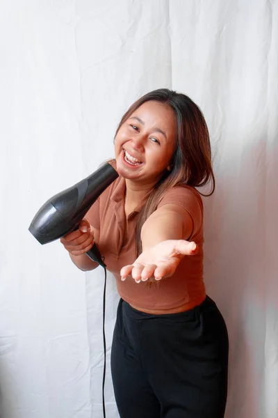 Young Asian woman holding a hair dryer and using the hair dryer