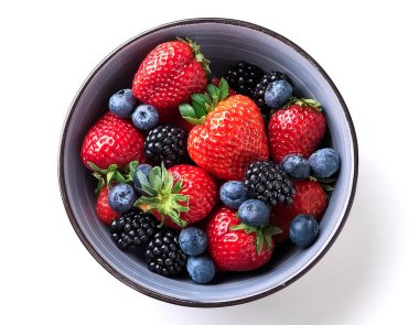 Mixed berries, strawberries, blueberries and blackberries in a bowl on white background