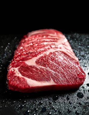 Su damlalı Japon wagyu filetosu, zifiri karanlık arka planda.