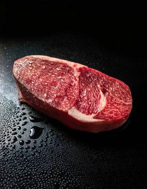 Su damlalı Japon wagyu filetosu, zifiri karanlık arka planda.