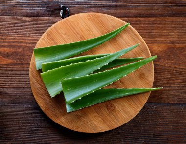 Ahşap kesme tahtasındaki aloe vera, ahşap bir arka planda izole edilmiş.