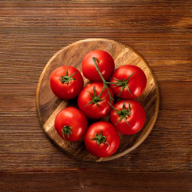 red tomatoes on a wooden cutting board, isolated against a wooden background