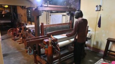 Hoi An, Vietnam: 13 Şubat 2023 - Vietnamlı kadın büyük bir dokuma tezgahında el yapımı ipekler örüyor