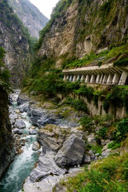 Yeşiller içinde yemyeşil bir vadi, Xiulin, Hualien, Tayvan 'daki Taroko Ulusal Parkı' ndaki Dokuz Viraj Tüneli 'nde dramatik kayalık uçurumlar arasında akan bir nehir manzarası.