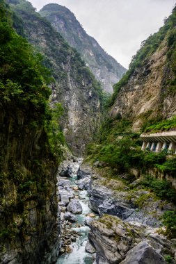 Yeşiller içinde yemyeşil bir vadi, Xiulin, Hualien, Tayvan 'daki Taroko Ulusal Parkı' ndaki Dokuz Viraj Tüneli 'nde dramatik kayalık uçurumlar arasında akan bir nehir manzarası.