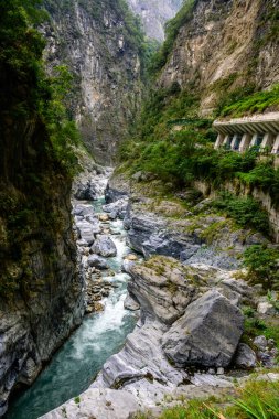 Yeşiller içinde yemyeşil bir vadi, Xiulin, Hualien, Tayvan 'daki Taroko Ulusal Parkı' ndaki Dokuz Viraj Tüneli 'nde dramatik kayalık uçurumlar arasında akan bir nehir manzarası.