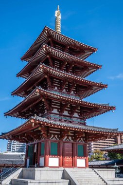 Shitenno-ji Gojunoto - Beş katlı bir pagoda Osaka, Japonya 'da açık mavi bir gökyüzüne karşı ayakta duruyor. Karmaşık kırmızı ahşap yapısı ve altın detayları geleneksel Japon işçiliğini gösteriyor..