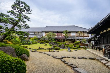 Japon Zen bahçesinde titizlikle düzenlenmiş kayalar, budanmış çalılar ve Japonya 'nın Osaka kentindeki Shitenno-ji Tapınağı yakınlarında geleneksel mimari sergileniyor..