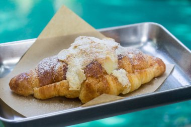 Metal üzerinde badem kruvasanı, havuzun önünde dene..