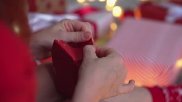 若い女性が友人や親戚のためにクリスマスプレゼントを梱包しています 女の子は赤い紙 色のリボンで新年のパッケージを作成します クリスマスの装飾 ホリデーシーズンの準備 — ストック動画