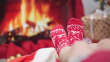 Noel ağacı ve şöminenin yanındaki Noel ışıklarının arka planında bir sürü güzel Noel hediyesi kutusunun yanında genç bir kadın. Atmosfer ve yeni yıl havası, altın ve kırmızı renkli şenlik dekoru..