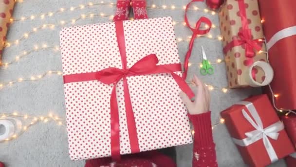クリスマスツリーの近くのクリスマスライトと部屋の暖炉を背景に 多くの美しいクリスマスギフトボックスの近くの若い女性 雰囲気と気分新年 金と赤のお祝いの装飾 — ストック動画