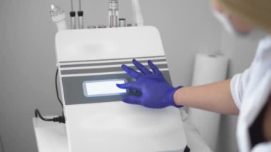 Yüz bakımı yenileniyor. Dişi bir kozmetikçi, kırışıklıkları mikro akımla gideriyor. Bir kız güzellik merkezinde kaldırıcı bir masaj yaptırır. Kozmetoloji kliniği, prosedürler.