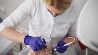 Yüz bakımı yenileniyor. Dişi bir kozmetikçi, kırışıklıkları mikro akımla gideriyor. Bir kız güzellik merkezinde kaldırıcı bir masaj yaptırır. Kozmetoloji kliniği, prosedürler.
