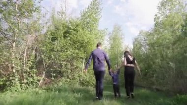 Mutlu genç bir aile parkta dinleniyor. Kocasıyla ve çocuğuyla birlikte bir eş doğada dinleniyor. Kavram: birlik, sevgi, karşılıklı anlayış, ortak ilgi alanı, birlikte zaman geçirme, boş zaman.