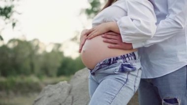 Güzel hamile kadın ve kocası göbeğine sarılıyorlar. Müstakbel anne ve babaları ilk çocuklarının doğmasını bekliyorlar. Genç bir ailenin hamileliği ve mutluluğu..