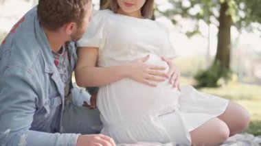 Güzel hamile kadın ve kocası göbeğine sarılıyorlar. Müstakbel anne ve babaları ilk çocuklarının doğmasını bekliyorlar. Genç bir ailenin hamileliği ve mutluluğu..