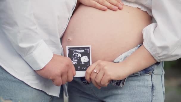 Красивая Беременная Женщина Муж Смотрят Фото Ребенка Животе Будущие Мама — стоковое видео
