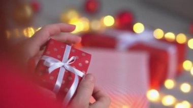 Kız kırmızı kağıtlı, renkli kurdeleli yeni yıl paketleri yapıyor. Genç bir kadın arkadaşları ve akrabaları için Noel hediyesi paketliyor. Noel süslemeleri, tatil sezonu hazırlıkları..