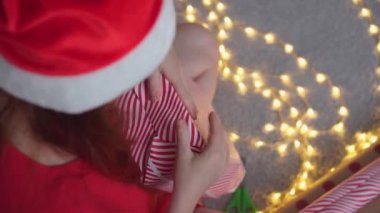 Kız kırmızı kağıtlı, renkli kurdeleli yeni yıl paketleri yapıyor. Genç bir kadın arkadaşları ve akrabaları için Noel hediyesi paketliyor. Noel süslemeleri, tatil sezonu hazırlıkları..