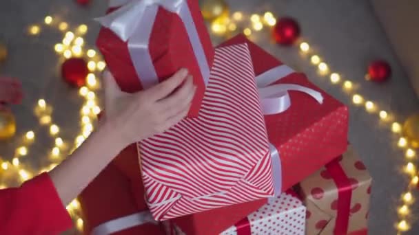 女の子は赤い紙 色のリボンで新年のパッケージを作成します 若い女性が友人や親戚のためにクリスマスプレゼントを梱包しています クリスマスの装飾 ホリデーシーズンの準備 — ストック動画