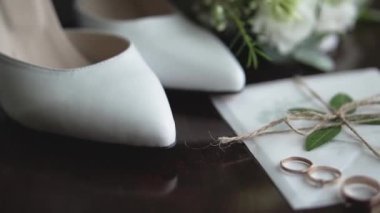 Düğün gereçleri. Düğün buketi olan beyaz düğün ayakkabıları. Gelin ve damat için altın alyanslar. Estetik tasarım ve düğün günü stili.