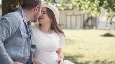 Güzel hamile kadın ve kocası göbeğine sarılıyorlar. Müstakbel anne ve babaları ilk çocuklarının doğmasını bekliyorlar. Genç bir ailenin hamileliği ve mutluluğu..