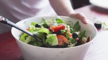 Taze sebze salatası. Turplar, domatesler, marullar, otlar ve zeytinlerden oluşan sağlıklı bir öğle yemeği. Mutfakta sağlıklı yemek pişirmek. Vejetaryen diyeti. Bir kadın salata karıştırıyor..