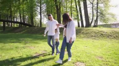 Mutlu genç bir aile parkta dinleniyor. Kocasıyla ve çocuğuyla birlikte bir eş doğada dinleniyor. Kavram: birlik, sevgi, karşılıklı anlayış, ortak ilgi alanı, birlikte zaman geçirme, boş zaman.