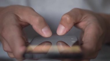 Genç bir adam akıllı telefonu kullanarak bir mesaj yolluyor, yakın plan. Cep telefonun elinde dursun. Mobil Teknoloji 5G konsepti ve insanların ekranda mesajlaşması ve okuması. Göz gezdir ve al.