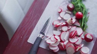 Mutfakta sağlıklı yemek pişirmek. Taze sebze salatası. Vejetaryen diyeti. Turplar, domatesler, marul, kokulu bitkiler ve zeytinlerle sağlıklı bir öğle yemeği yakın. Kadın salata keser ve karıştırır..