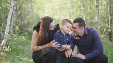 Mutlu genç bir aile parkta dinleniyor. Kocasıyla ve çocuğuyla birlikte bir eş doğada dinleniyor. Kavram: birlik, sevgi, karşılıklı anlayış, ortak ilgi alanı, birlikte zaman geçirme, boş zaman.
