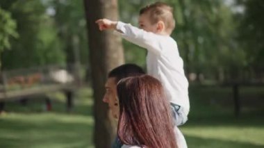 Mutlu genç bir aile parkta dinleniyor. Kocasıyla ve çocuğuyla birlikte bir eş doğada dinleniyor. Kavram: birlik, sevgi, karşılıklı anlayış, ortak ilgi alanı, birlikte zaman geçirme, boş zaman.