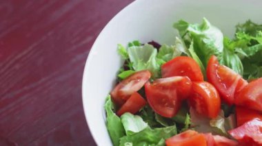 Taze sebze salatası. Turplar, domatesler, marullar, otlar ve zeytinlerden oluşan sağlıklı bir öğle yemeği. Mutfakta sağlıklı yemek pişirmek. Vejetaryen diyeti. Bir kadın salata karıştırıyor..
