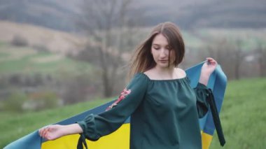 Genç, güzel esmer kız çimlerin ve çiçeklerin arasında doğada. Kız çimlerin üzerinde yürüyor ve doğada dinleniyor. Doğal kozmetik ürünleri ve cilt bakımı.