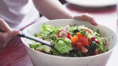 Taze sebze salatası. Turplar, domatesler, marullar, otlar ve zeytinlerden oluşan sağlıklı bir öğle yemeği. Mutfakta sağlıklı yemek pişirmek. Vejetaryen diyeti. Bir kadın salata karıştırıyor..