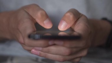 Genç bir adam akıllı telefonu kullanarak bir mesaj yolluyor, yakın plan. Cep telefonun elinde dursun. Mobil Teknoloji 5G konsepti ve insanların ekranda mesajlaşması ve okuması. Göz gezdir ve al.