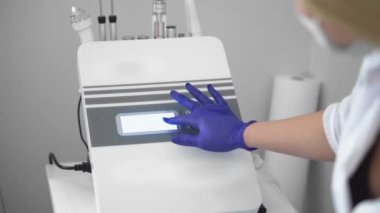 Kozmetolojide donanım prosedürü. Güzellik kliniğinde soyulan, fonoresis, masaj ve yüz gerdirme. Kozmetik uzmanı kırışıklıkları mikro akımla düzeltiyor.