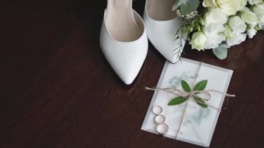 Düğün buketi olan beyaz düğün ayakkabıları. Gelin ve damat için altın alyanslar. Beyaz düğün 