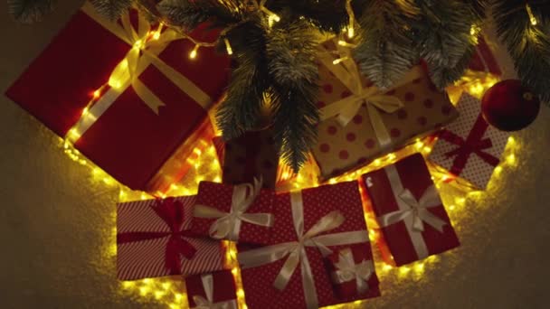 ライト ボールやプレゼントで飾られたクリスマスツリー 新年の休日の雰囲気 冬のおとぎ話や自宅でクリスマスの精神 緑の木の下にリボン付きの赤いパッケージをプレゼント スローモーション — ストック動画