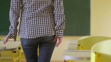 Sınıfta bir bayan öğretmen dolaşıyor, masanın üzerine kağıtlar seriyor. Kız okulda öğrencilik yapıyor. Çocuk eğitimi, çocuklar için eğitim konsepti.