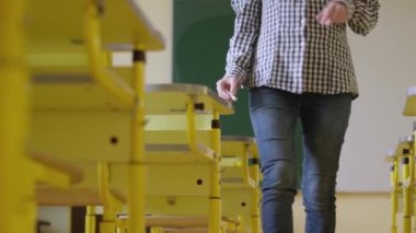 Sınıfta bir bayan öğretmen dolaşıyor, masanın üzerine kağıtlar seriyor. Kız okulda öğrencilik yapıyor. Çocuk eğitimi, çocuklar için eğitim konsepti.