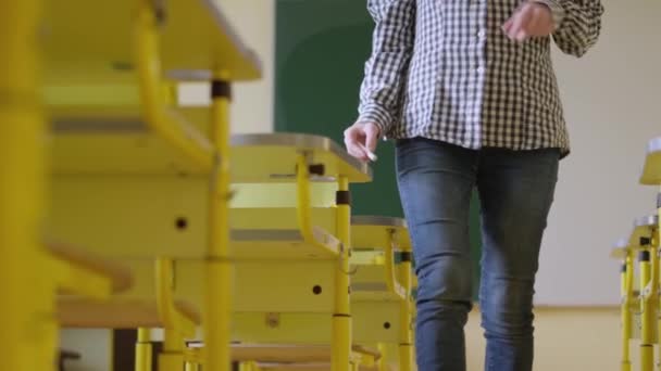Female Teacher Walks Classroom Spreads Sheets Paper Desk Girl Student — Vídeo de stock