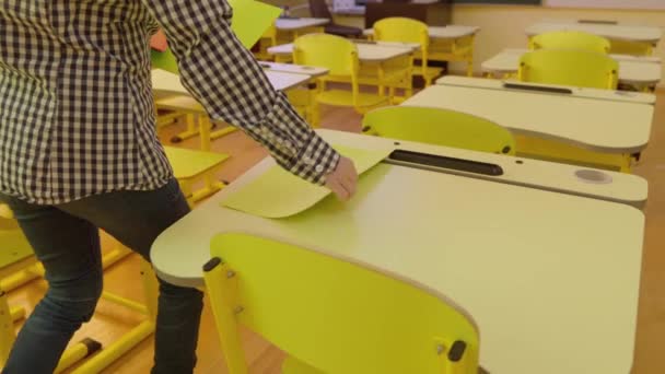 Female Teacher Walks Classroom Spreads Sheets Paper Desk Girl Student — Vídeos de Stock