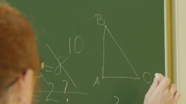 一个女生在绿色的黑板上写字 学校董事会附近的女教师 一只手用白粉笔在黑板上写下信息 教育进程的概念 — 图库视频影像