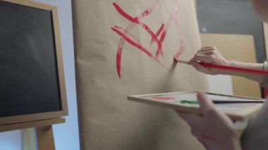 A talented, innovative woman artist paints with a brush on canvas, using multi-colored paints, she creates a colorful, emotional, sensual picture. Modern artist creates abstract modern art. Girl draws