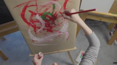 A talented, innovative woman artist paints with a brush on canvas, using multi-colored paints, she creates a colorful, emotional, sensual picture. Modern artist creates abstract modern art. Girl draws