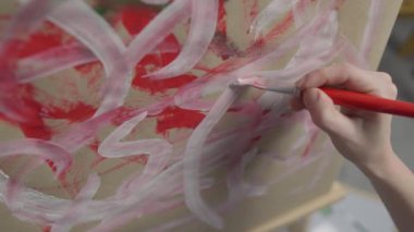 A talented, innovative woman artist paints with a brush on canvas, using multi-colored paints, she creates a colorful, emotional, sensual picture. Modern artist creates abstract modern art. Girl draws