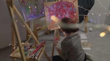 A talented, innovative woman artist paints with a brush on canvas, using multi-colored paints, she creates a colorful, emotional, sensual picture. Modern artist creates abstract modern art. Girl draws