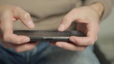 A mans finger touches a monitor to scroll a page on a mobile phone. Viewing photos and documents in the smartphone library. A man in his hands uses a smartphone, turns pages.